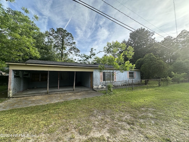 exterior space featuring driveway, fence, a carport, and a front yard