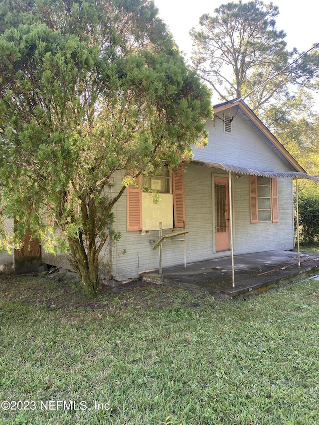 view of front of property featuring a patio, brick siding, and a front yard