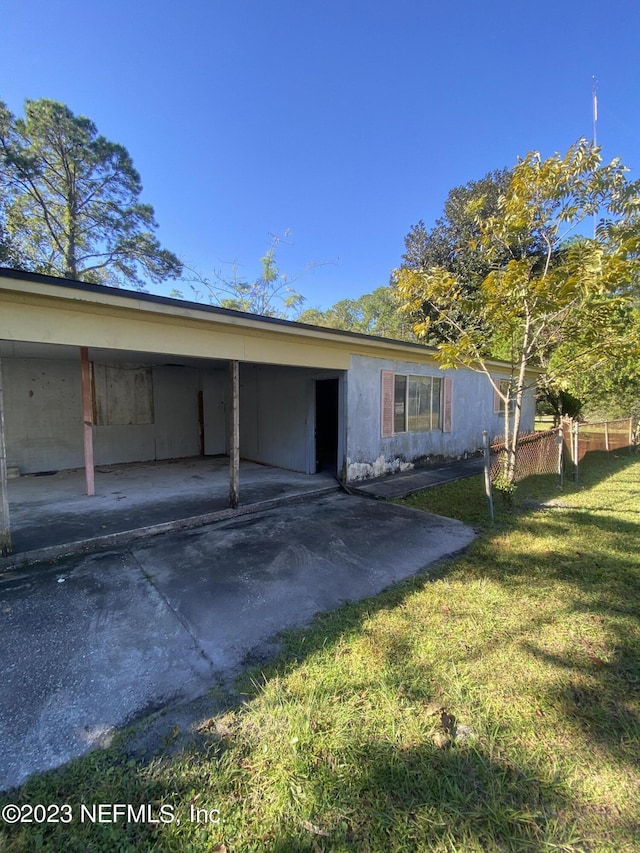 exterior space with a carport, a front yard, fence, and driveway