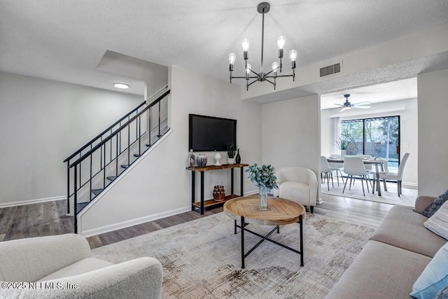 living area with baseboards, visible vents, stairway, wood finished floors, and an inviting chandelier