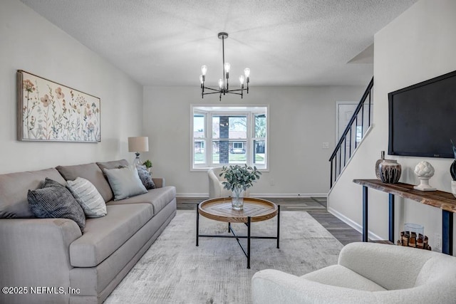 living area with baseboards, stairway, wood finished floors, an inviting chandelier, and a textured ceiling