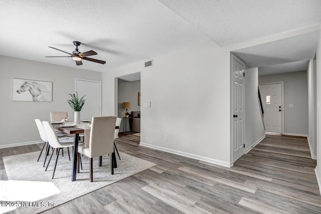 dining space featuring a textured ceiling, visible vents, and wood finished floors