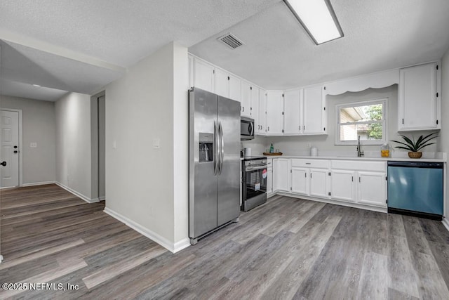 kitchen featuring white cabinetry, visible vents, stainless steel appliances, and a sink