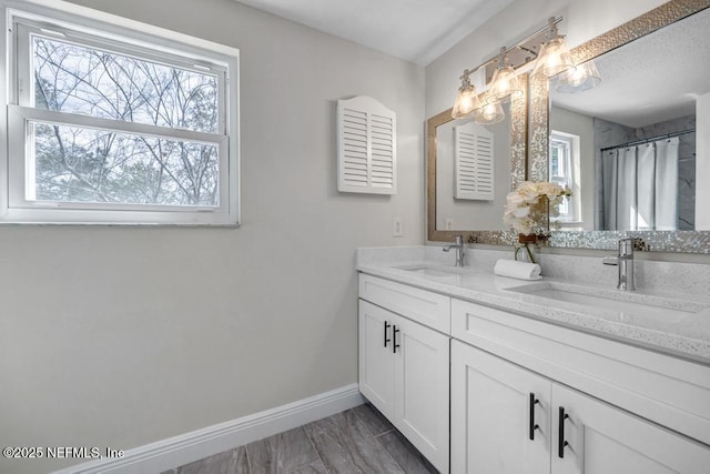 bathroom with baseboards, a sink, and a healthy amount of sunlight