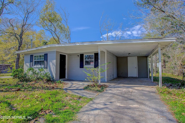 view of front facade featuring aphalt driveway, an attached carport, and concrete block siding