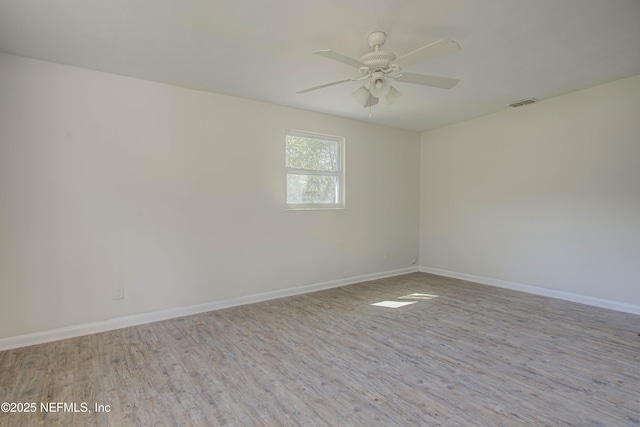 spare room featuring wood finished floors, a ceiling fan, and baseboards