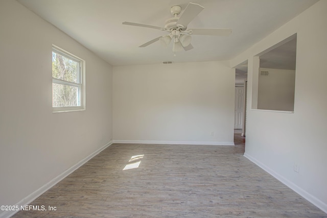 spare room with ceiling fan, wood finished floors, visible vents, and baseboards