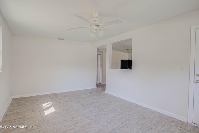 unfurnished room with ceiling fan, wood finished floors, and baseboards