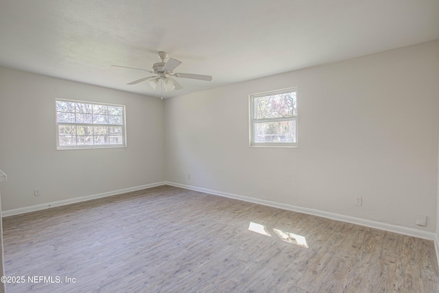 spare room with a wealth of natural light, baseboards, and wood finished floors