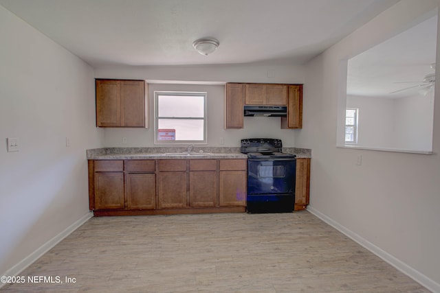 kitchen with black range with electric cooktop, light wood-style flooring, under cabinet range hood, a sink, and brown cabinetry