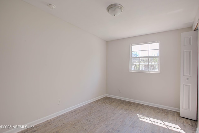 spare room featuring baseboards and wood finished floors