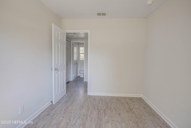 empty room with light wood-style flooring, visible vents, and baseboards