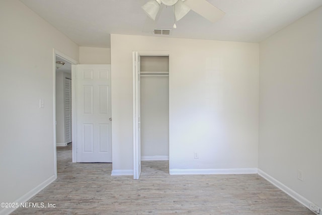 unfurnished bedroom with baseboards, visible vents, a ceiling fan, wood finished floors, and a closet