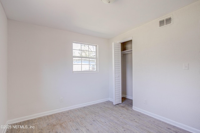 unfurnished bedroom with a closet, visible vents, baseboards, and wood finished floors