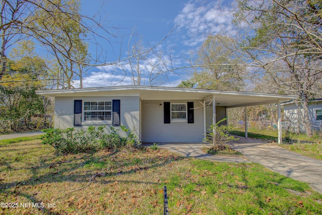 ranch-style home featuring a front lawn, concrete block siding, an attached carport, and concrete driveway