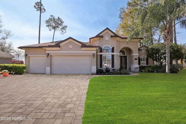 mediterranean / spanish house with an attached garage, a front yard, decorative driveway, and stucco siding