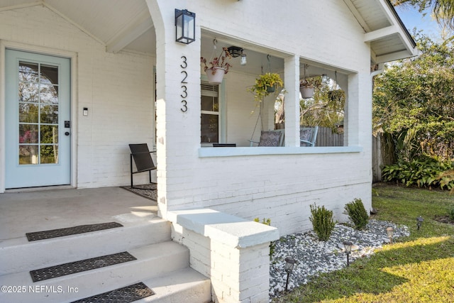 doorway to property featuring brick siding and a porch