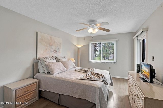 bedroom featuring baseboards, a textured ceiling, a ceiling fan, and wood finished floors