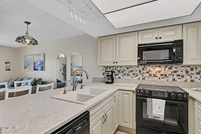 kitchen featuring cream cabinets, a sink, light countertops, backsplash, and black appliances