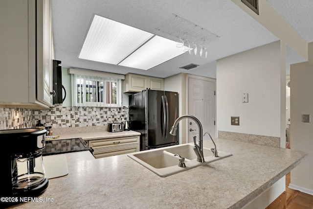 kitchen featuring a peninsula, a sink, visible vents, backsplash, and black appliances