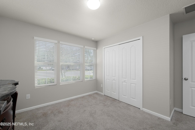 unfurnished bedroom featuring a closet, visible vents, baseboards, and carpet floors