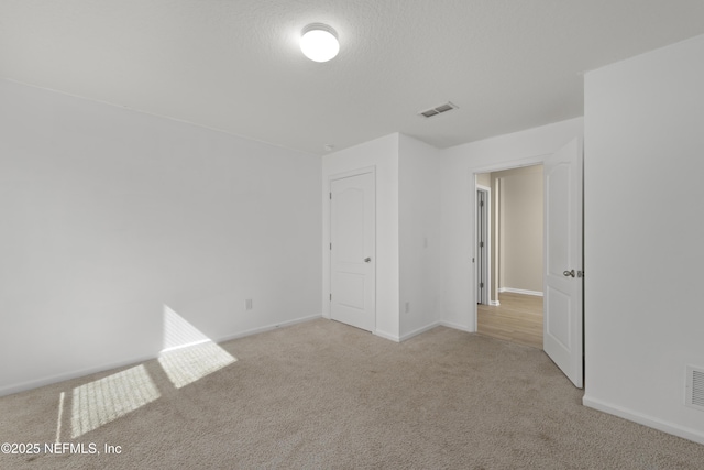 empty room featuring baseboards, visible vents, carpet floors, and a textured ceiling