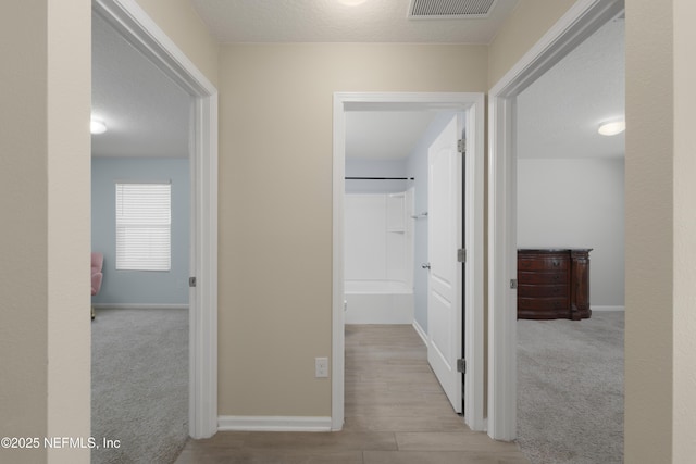 hall featuring carpet flooring, baseboards, and visible vents