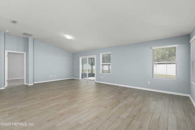 spare room with visible vents, baseboards, lofted ceiling, and wood finished floors