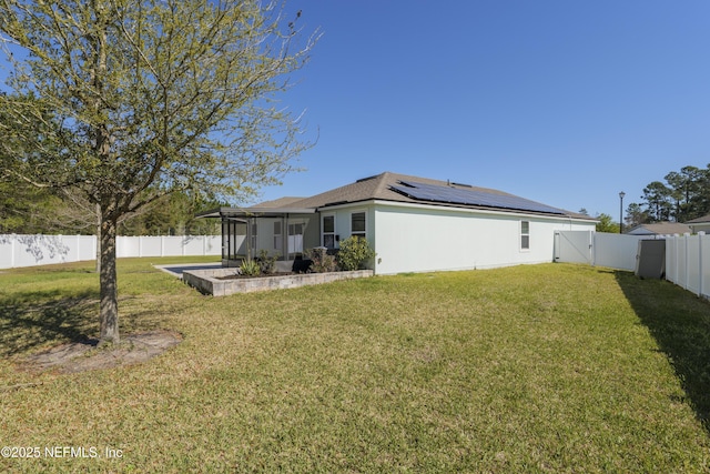 rear view of house with a lawn, a sunroom, a fenced backyard, and a gate