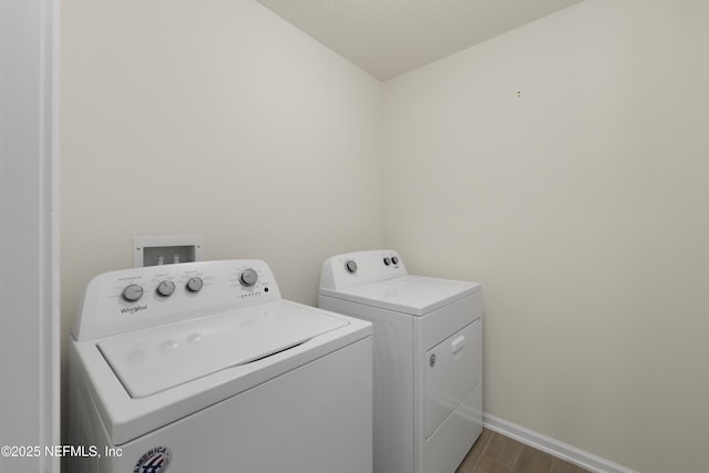 laundry area with dark wood finished floors, laundry area, washing machine and dryer, and baseboards