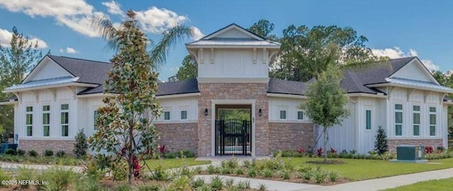 view of front of home with a front yard, central air condition unit, a gate, and stone siding