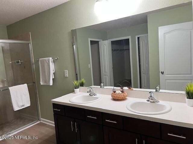 738 Seville Pkwy, Saint Augustine, FL 32086 - bathroom with a stall shower, a textured ceiling, double vanity, and a sink