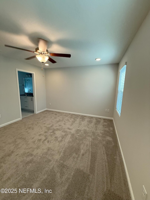 carpeted empty room featuring ceiling fan and baseboards