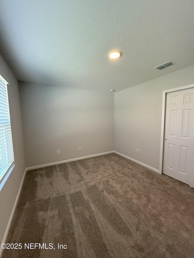 carpeted empty room with visible vents, a textured ceiling, and baseboards