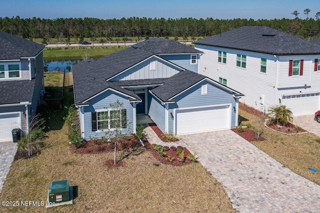 view of front facade with roof with shingles, decorative driveway, and an attached garage