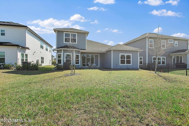 rear view of property featuring a yard and fence