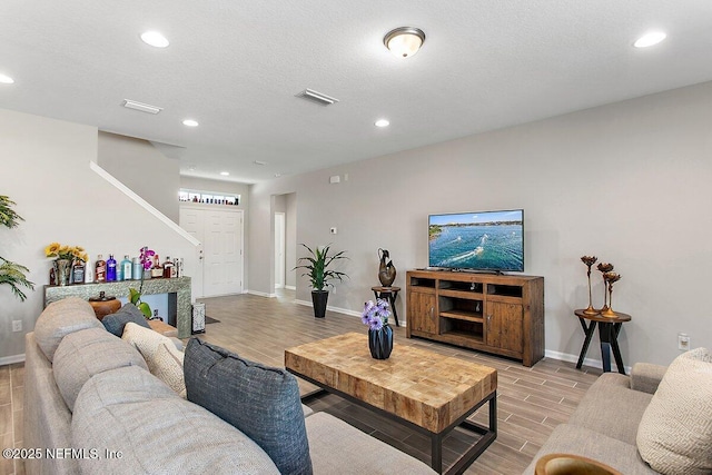 living area with wood tiled floor, visible vents, baseboards, and recessed lighting