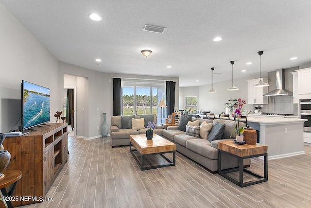 living room with recessed lighting, visible vents, and wood finish floors