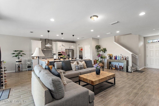 living area featuring wood tiled floor, stairs, visible vents, and recessed lighting