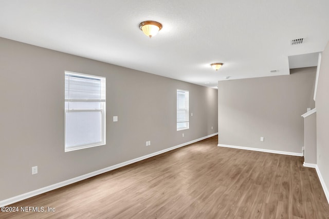 empty room with visible vents, baseboards, and wood finished floors