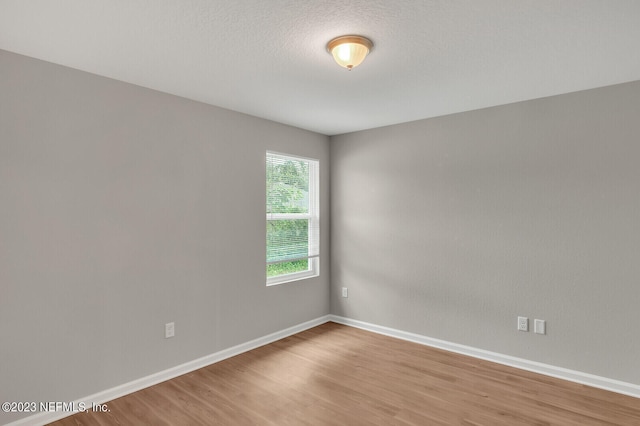 unfurnished room featuring a textured ceiling, wood finished floors, and baseboards