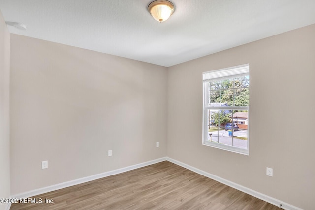 spare room with baseboards and wood finished floors