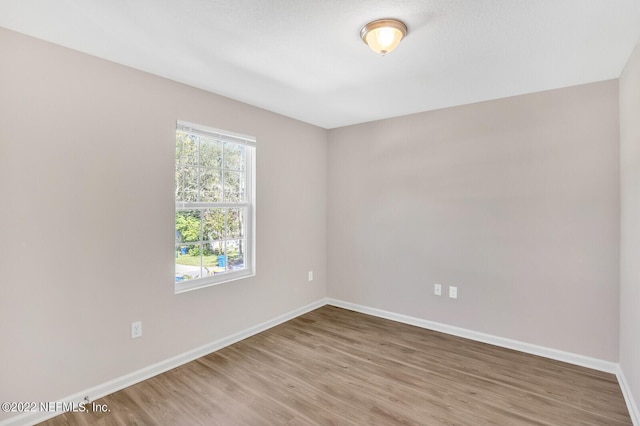 spare room with baseboards and wood finished floors