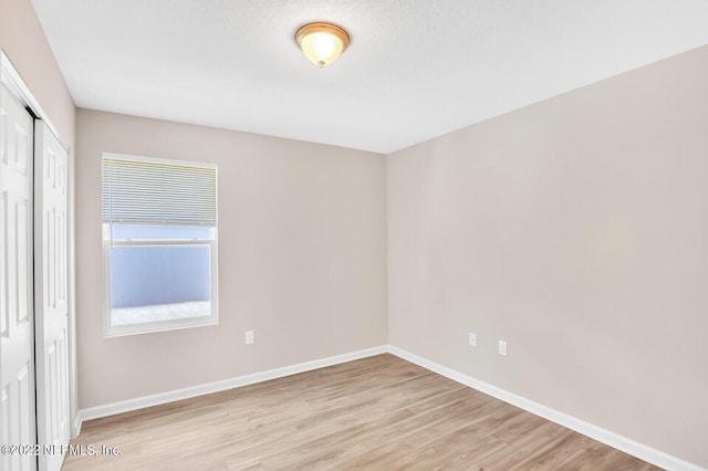 spare room featuring baseboards and light wood-style floors