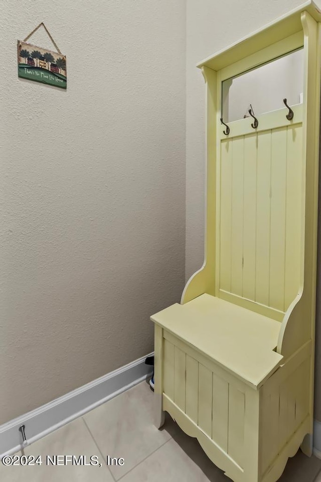 mudroom featuring tile patterned flooring, baseboards, and a textured wall