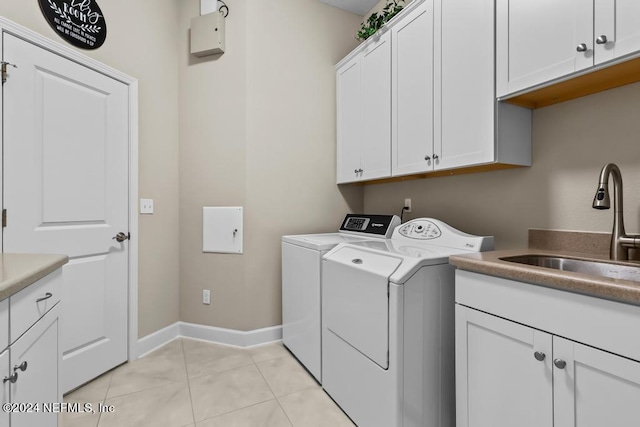 laundry area with cabinet space, baseboards, washer and dryer, a sink, and light tile patterned flooring