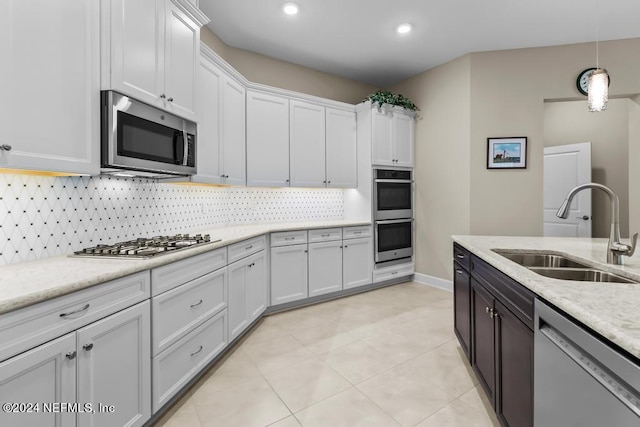 kitchen with a sink, white cabinets, appliances with stainless steel finishes, decorative backsplash, and decorative light fixtures