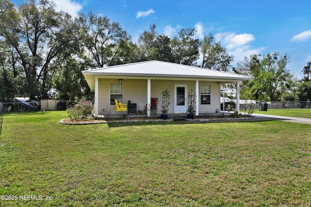 view of front of home featuring covered porch, fence, metal roof, and a front yard