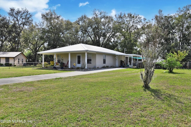 view of front of home featuring metal roof, concrete driveway, a front yard, and fence