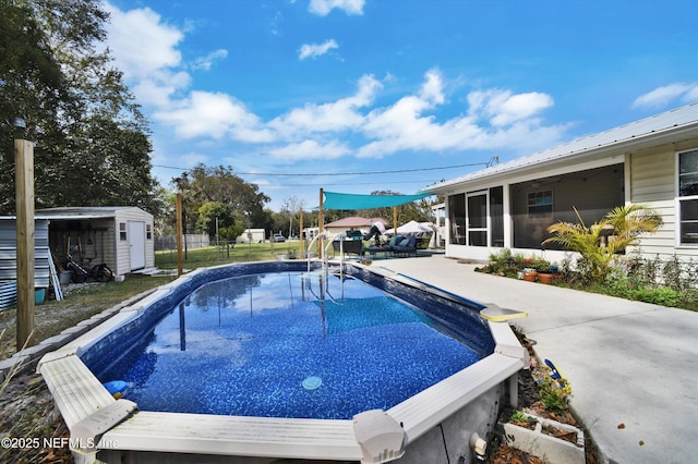 outdoor pool with a storage shed, a sunroom, an outbuilding, fence, and a patio area